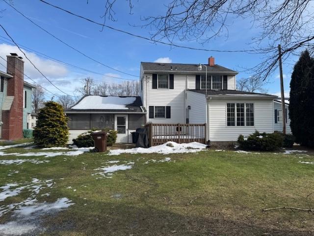 rear view of house with a wooden deck and a lawn