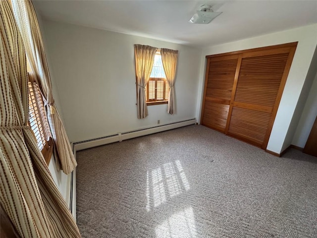 unfurnished bedroom featuring carpet floors, a closet, and a baseboard heating unit