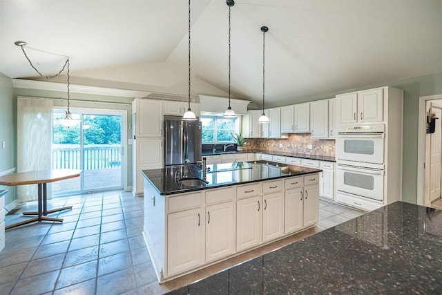 8730 Peffer Rd, Fairview, PA 16415 - kitchen with freestanding refrigerator, white double oven, vaulted ceiling, tasteful backsplash, and white cabinets