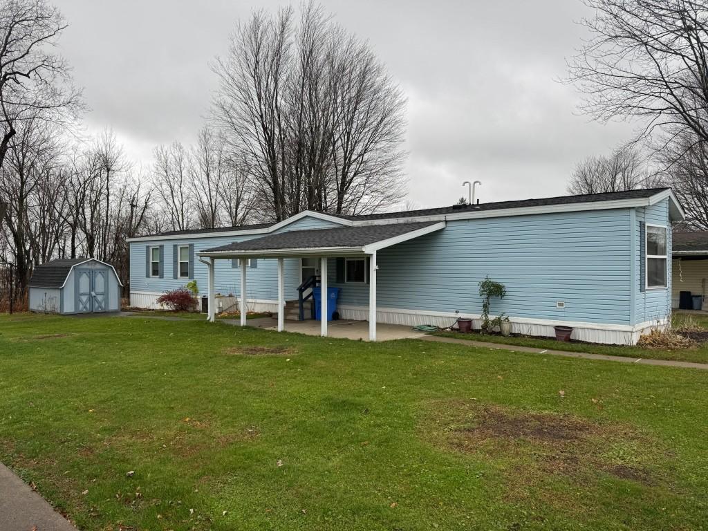 back of property featuring a storage unit, a patio area, and a lawn