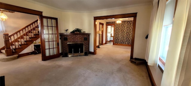 living area with ornamental molding, carpet flooring, a fireplace, and stairs