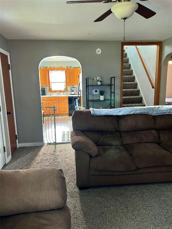 living room with ceiling fan, sink, and carpet