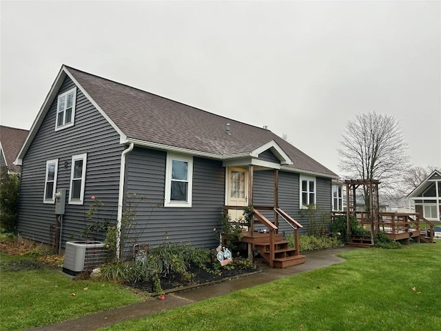 rear view of house featuring cooling unit, a wooden deck, and a lawn