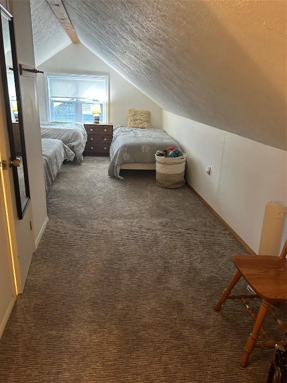 bedroom featuring dark colored carpet, a textured ceiling, and lofted ceiling