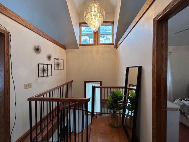 stairs featuring hardwood / wood-style flooring, an inviting chandelier, and vaulted ceiling