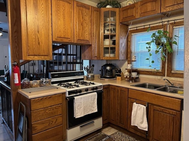 kitchen featuring white gas range, sink, and light tile patterned floors