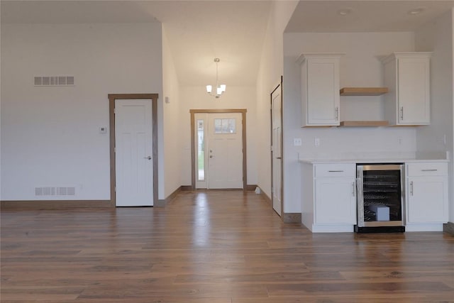 foyer featuring dark hardwood / wood-style floors, beverage cooler, and a chandelier