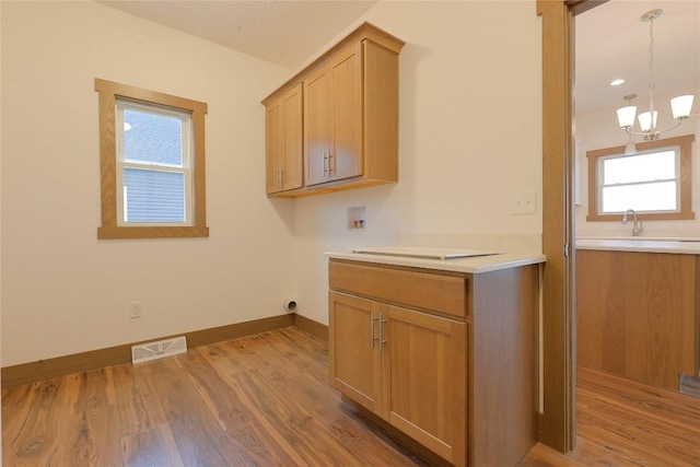 laundry area featuring sink, cabinets, a notable chandelier, hookup for a washing machine, and hardwood / wood-style flooring