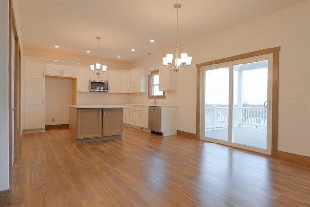 kitchen with pendant lighting, a center island, white cabinets, stainless steel appliances, and a chandelier