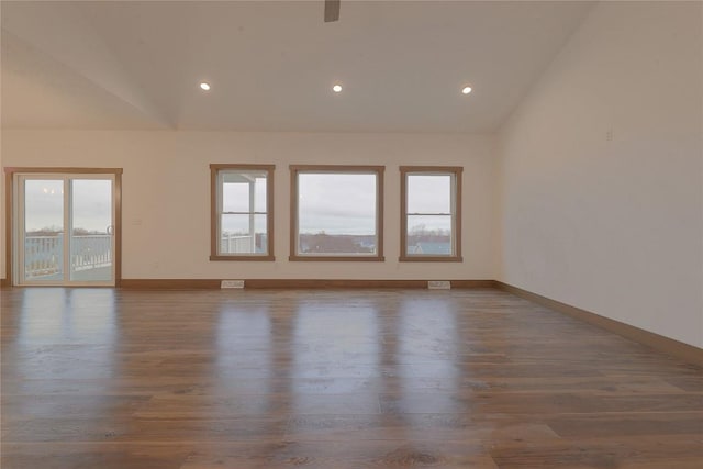 empty room with dark wood-type flooring and lofted ceiling