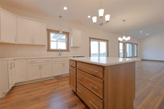 kitchen featuring decorative light fixtures, hardwood / wood-style flooring, a notable chandelier, white cabinets, and a kitchen island