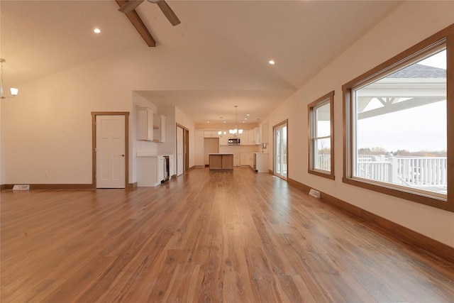 unfurnished living room featuring hardwood / wood-style floors, lofted ceiling with beams, and ceiling fan with notable chandelier