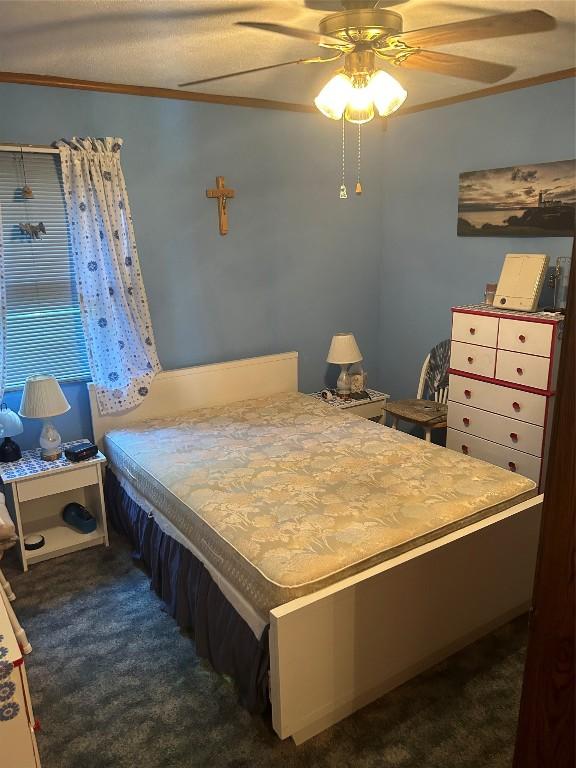 bedroom featuring ceiling fan, crown molding, and dark carpet