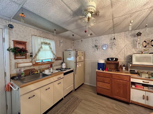 kitchen featuring light wood-type flooring, white appliances, ceiling fan, and sink