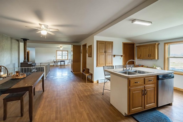 kitchen featuring vaulted ceiling, a kitchen island with sink, sink, dishwasher, and a wood stove