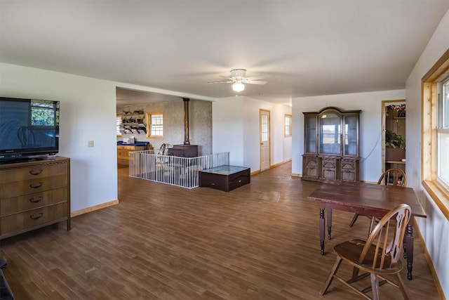 living room with dark hardwood / wood-style floors, ceiling fan, and a wood stove