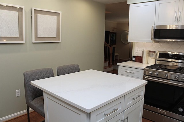 1351 Top Rd, Erie, PA 16505 - kitchen with appliances with stainless steel finishes, a center island, light countertops, a breakfast bar, and dark wood finished floors