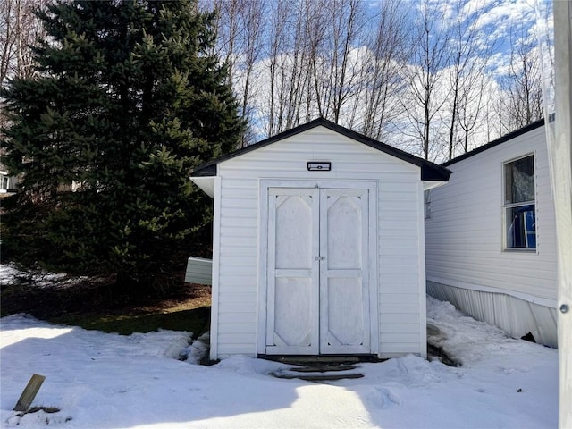 snow covered structure with a storage unit and an outdoor structure