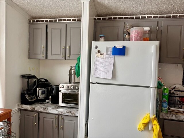 kitchen featuring a textured ceiling, gray cabinets, and freestanding refrigerator