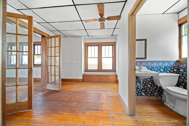 interior space with french doors, a paneled ceiling, hardwood / wood-style flooring, and toilet