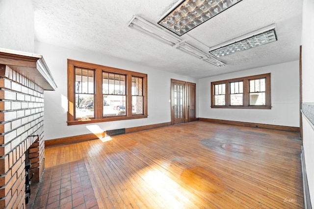 empty room with a fireplace, a textured ceiling, and hardwood / wood-style flooring