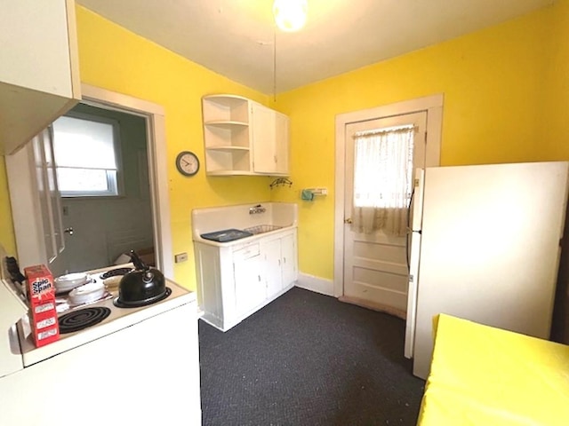 kitchen featuring open shelves, light countertops, freestanding refrigerator, a sink, and baseboards