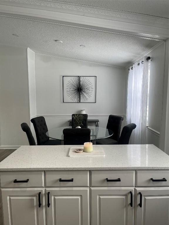 interior space featuring lofted ceiling, light stone countertops, white cabinetry, and a textured ceiling