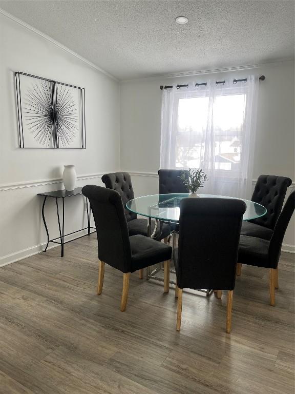 dining space featuring crown molding, a textured ceiling, baseboards, and wood finished floors