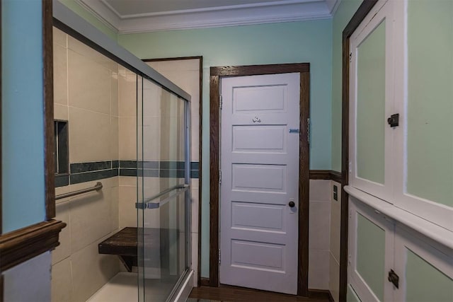 bathroom with crown molding, a shower with door, and tile walls