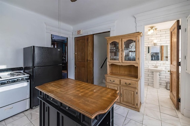 kitchen featuring black fridge, sink, a center island, and white gas range oven