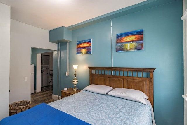 bedroom with dark hardwood / wood-style floors and white fridge