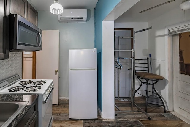 kitchen with an AC wall unit, tasteful backsplash, sink, dark brown cabinetry, and white appliances