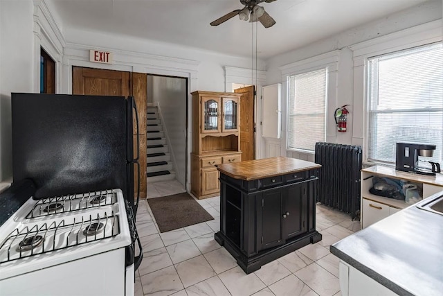 kitchen featuring refrigerator, a center island, radiator heating unit, ceiling fan, and white gas range oven