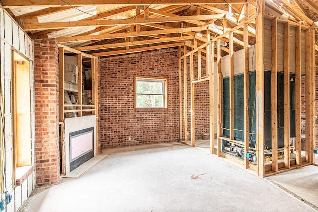 miscellaneous room with brick wall and vaulted ceiling