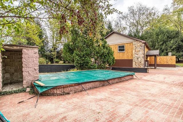 view of swimming pool featuring a storage unit and a patio area