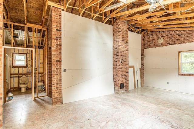 misc room with lofted ceiling and brick wall