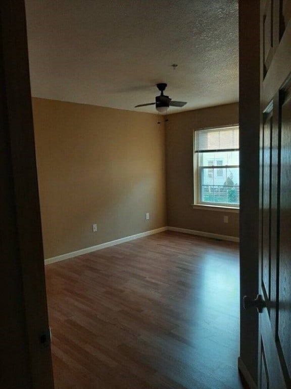 spare room with hardwood / wood-style floors, ceiling fan, and a textured ceiling