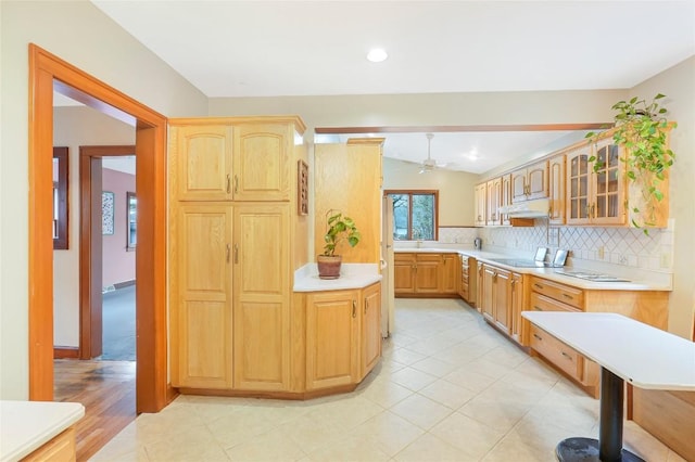 kitchen with light countertops, vaulted ceiling, black electric stovetop, decorative backsplash, and glass insert cabinets