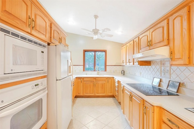 kitchen with a sink, decorative backsplash, white appliances, ceiling fan, and under cabinet range hood
