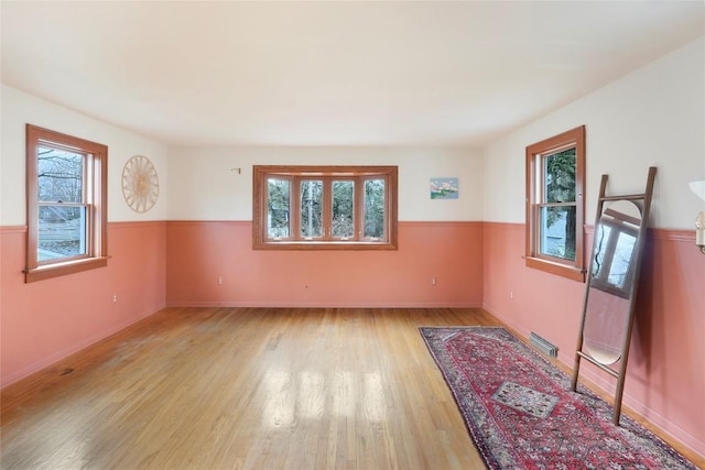 unfurnished room with a wealth of natural light, light wood finished floors, and visible vents