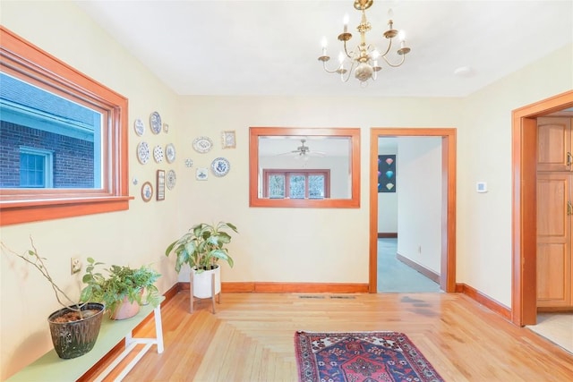 hall featuring baseboards, an inviting chandelier, and parquet floors