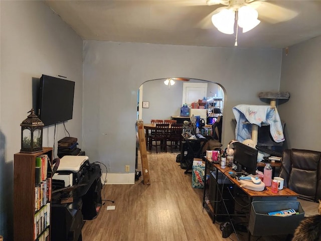 interior space featuring arched walkways, a ceiling fan, and wood finished floors