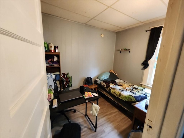 bedroom with a drop ceiling and wood finished floors
