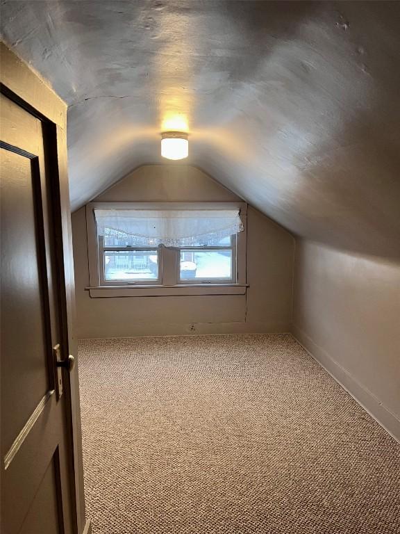 bonus room featuring vaulted ceiling and carpet floors