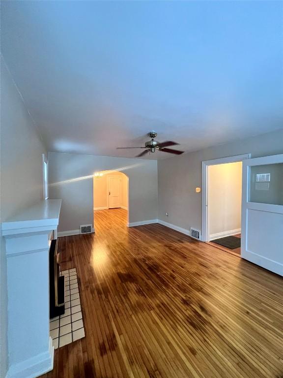 unfurnished living room featuring hardwood / wood-style flooring, ceiling fan, a fireplace, and vaulted ceiling