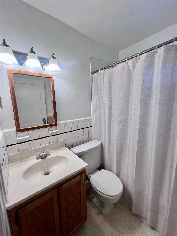 bathroom featuring vanity, toilet, and tile walls