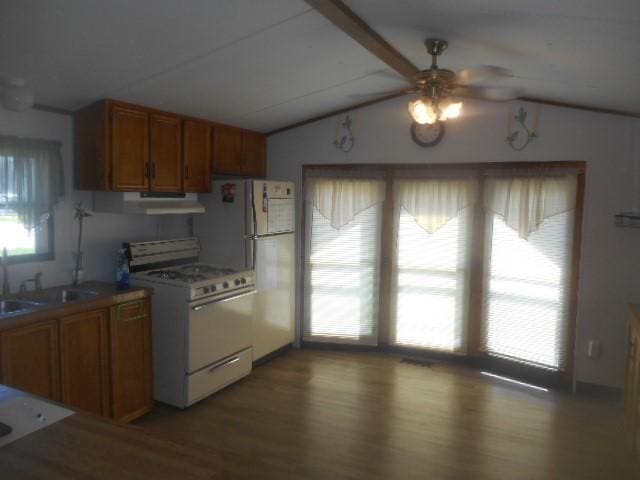 kitchen with brown cabinetry, vaulted ceiling with beams, wood finished floors, and white appliances