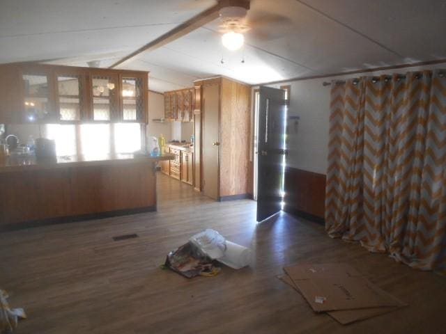 empty room featuring vaulted ceiling with beams, ceiling fan, baseboards, and wood finished floors