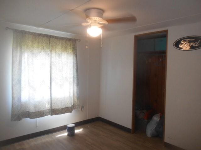 unfurnished room with a ceiling fan, baseboards, and wood finished floors