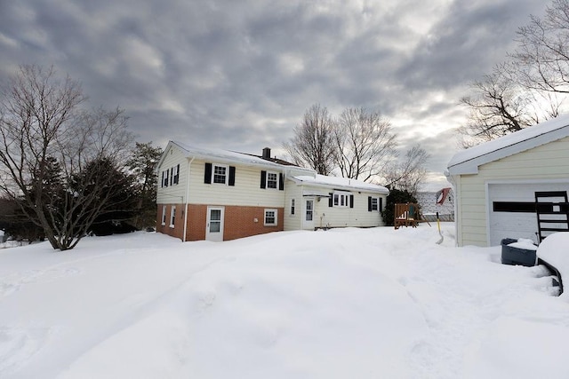 snow covered house with a garage and brick siding